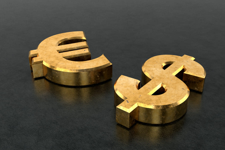 Simbol euro dan dolar berwarna emas di atas permukaan gelap.